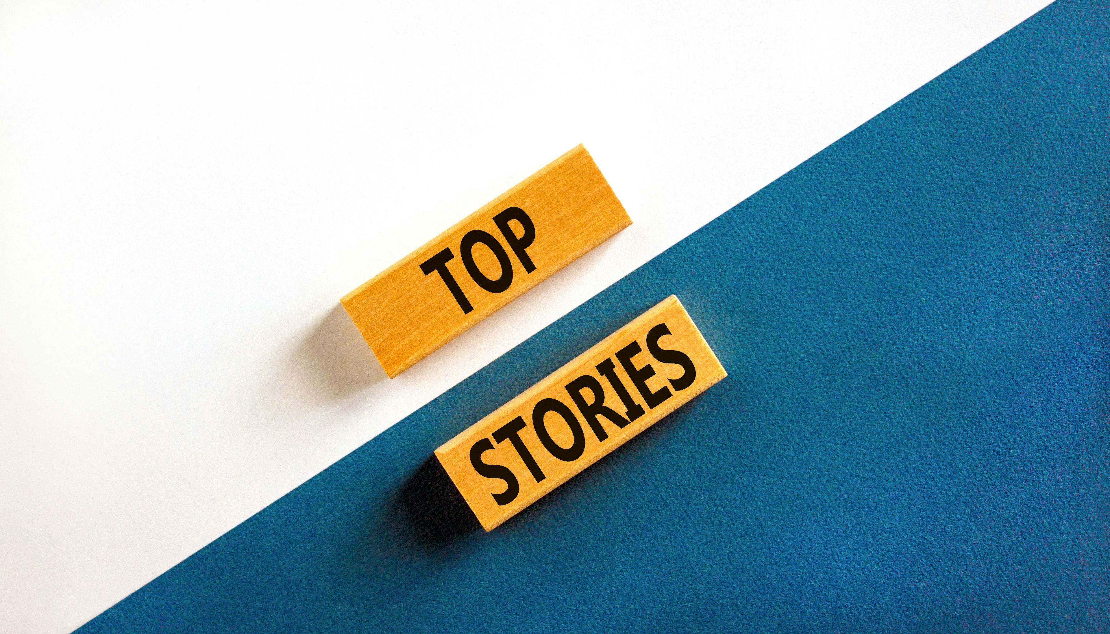 Top stories symbol. Concept words Top stories on wooden blocks on a beautiful blue table white background. Business story and top stories concept, copy space. | Image Credit: © Dzmitry - stock.adobe.com