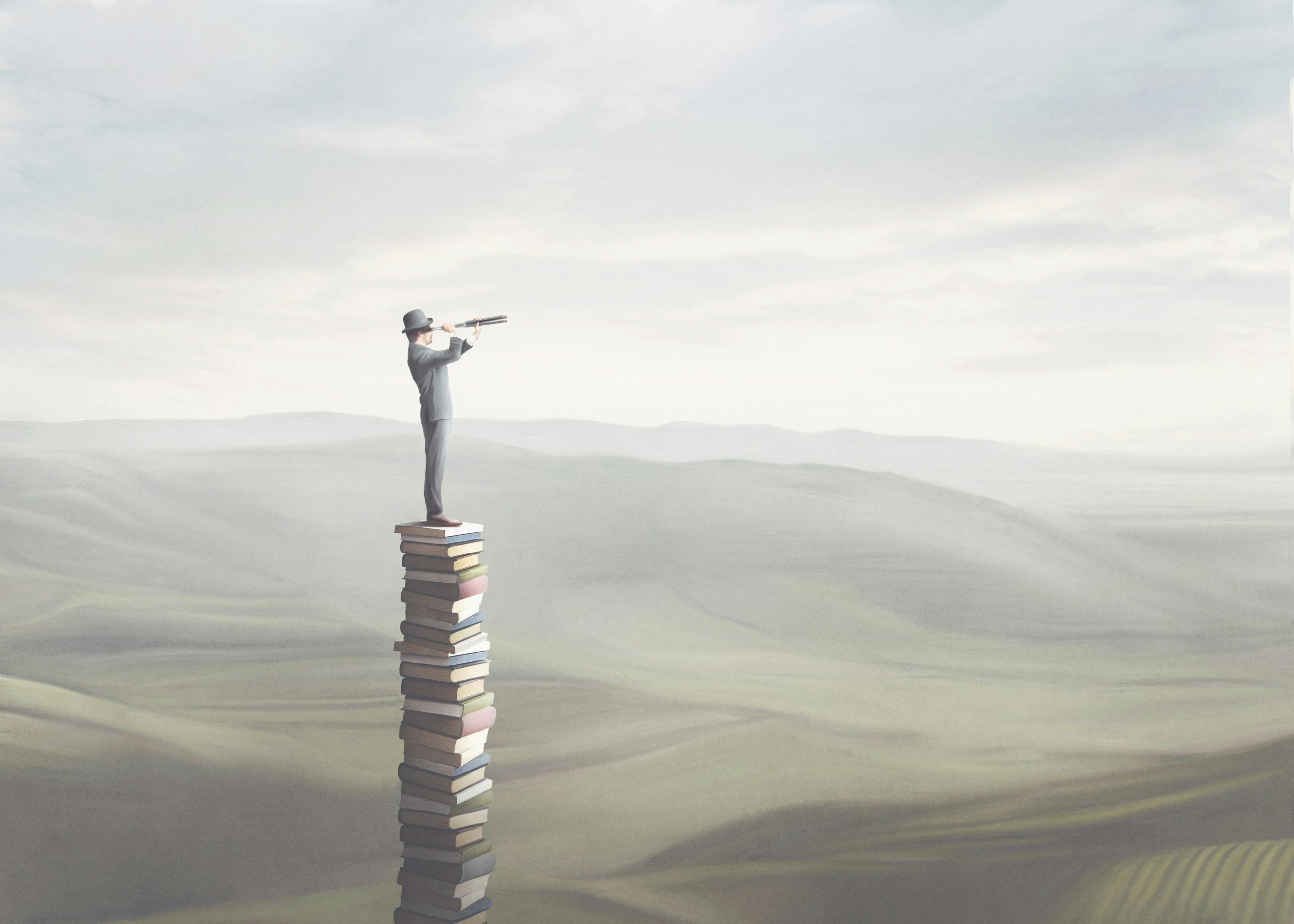 man standing on books looking out at the view – visual representation of overcoming ignorance