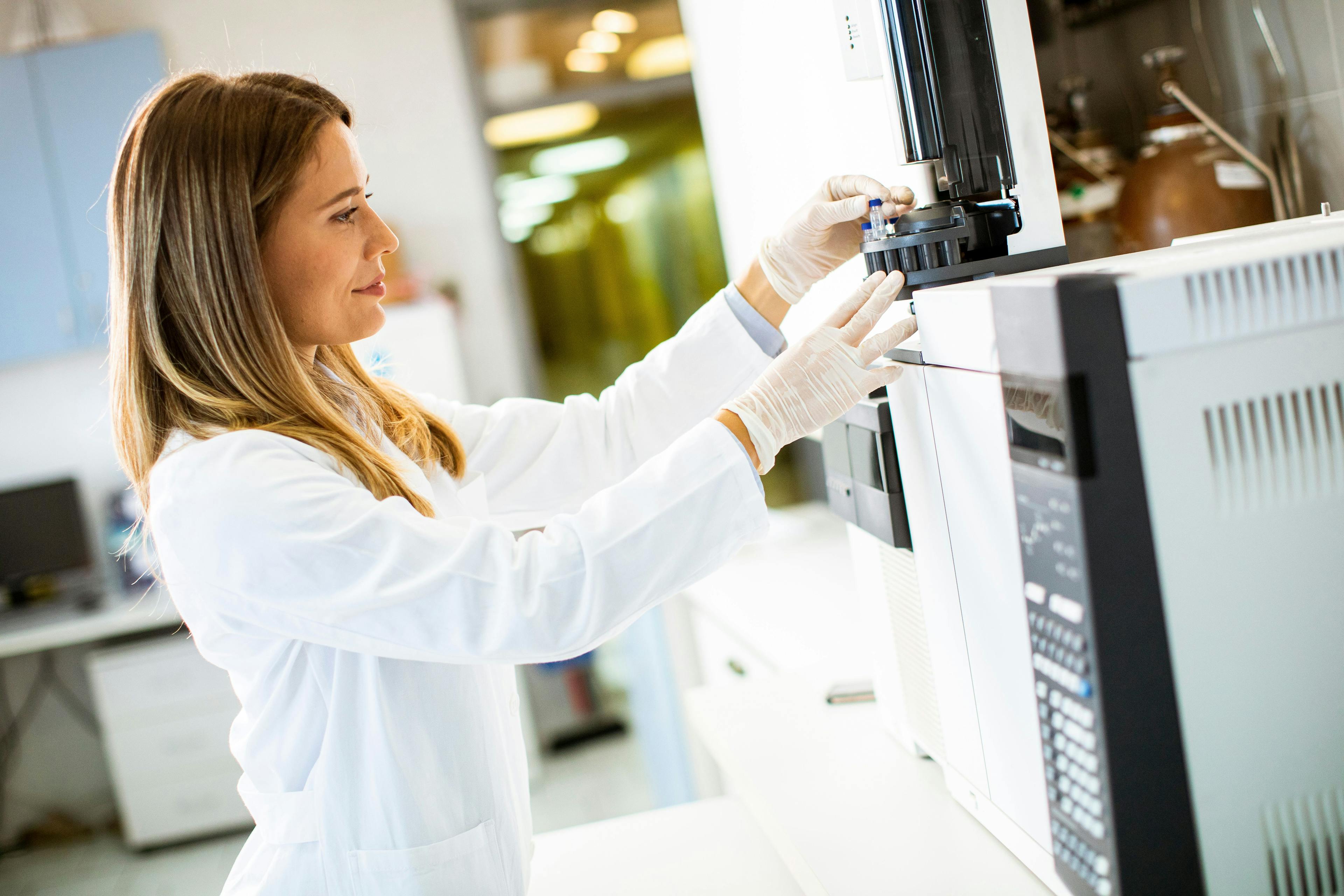 Female scientist in a white lab coat putting vial with a sample for an analysis on a gas chromatograph in biomedical lab | Image Credit: © BGStock72 - stock.adobe.com