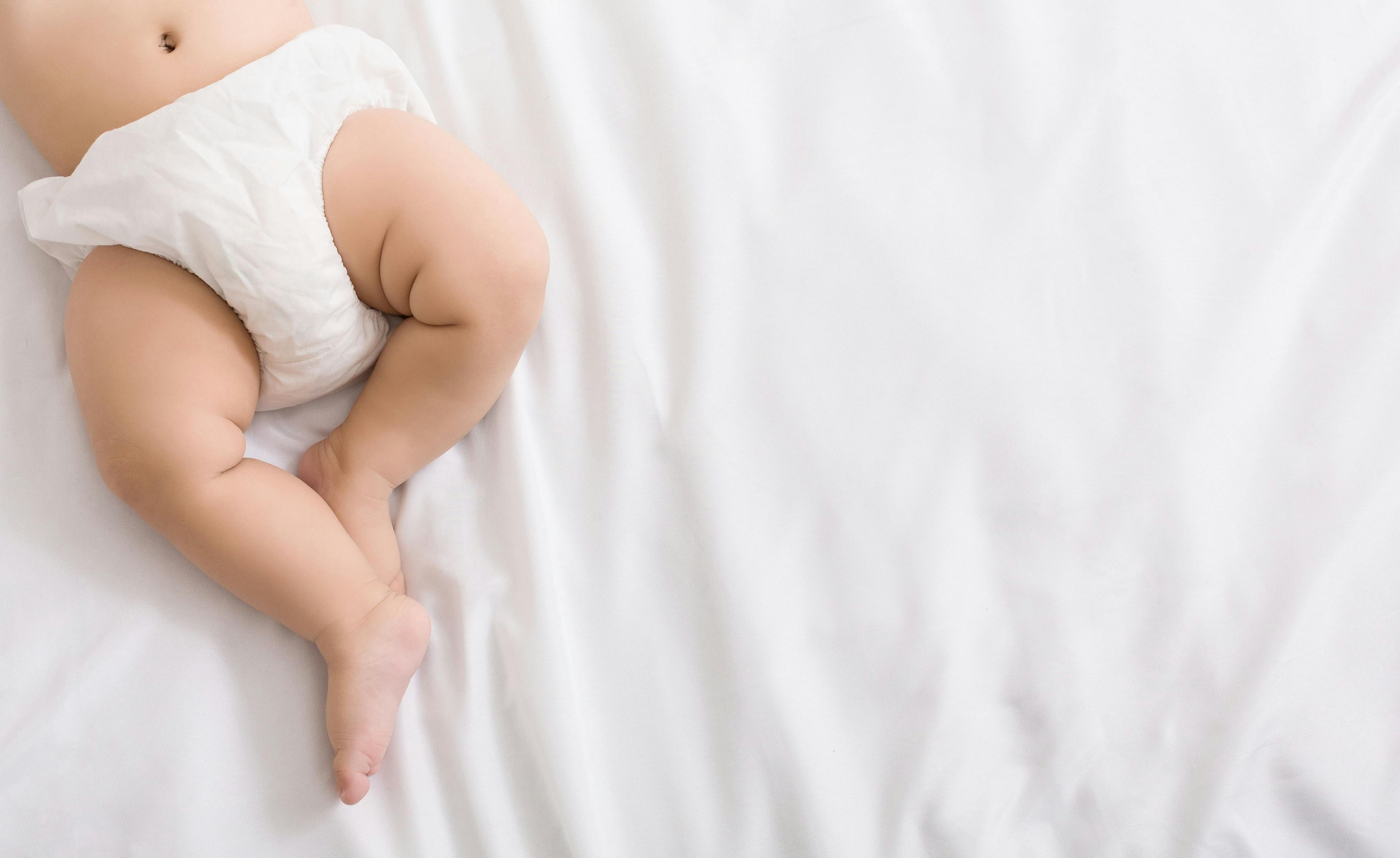Baby legs and bottom in diaper on bed | Image Credit: © Prostock-studio - stock.adobe.com