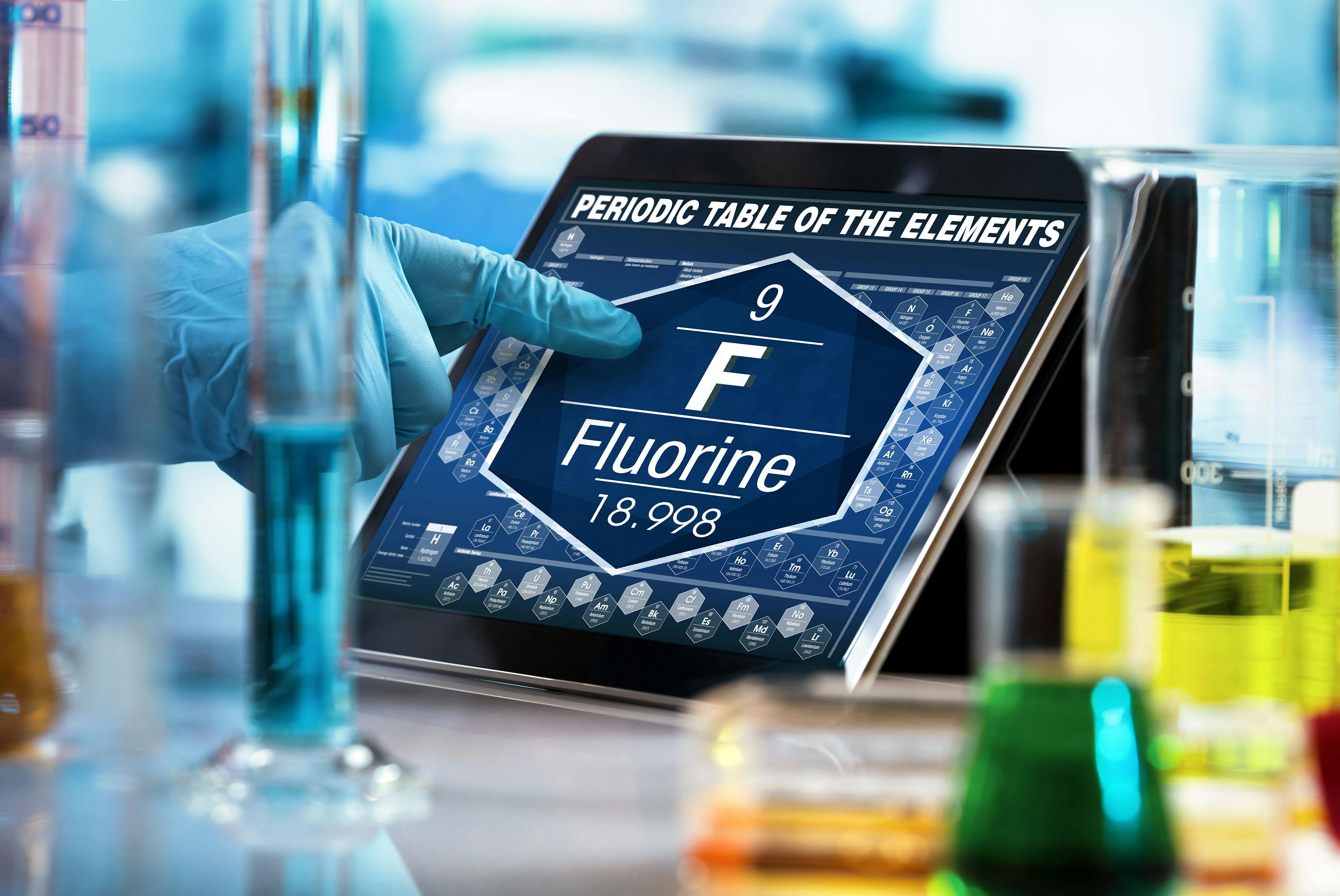 scientist consulting on the digital tablet data of the chemical element Fluorine F / researcher working on the computer with the periodic table of elements | Image Credit: © angellodeco