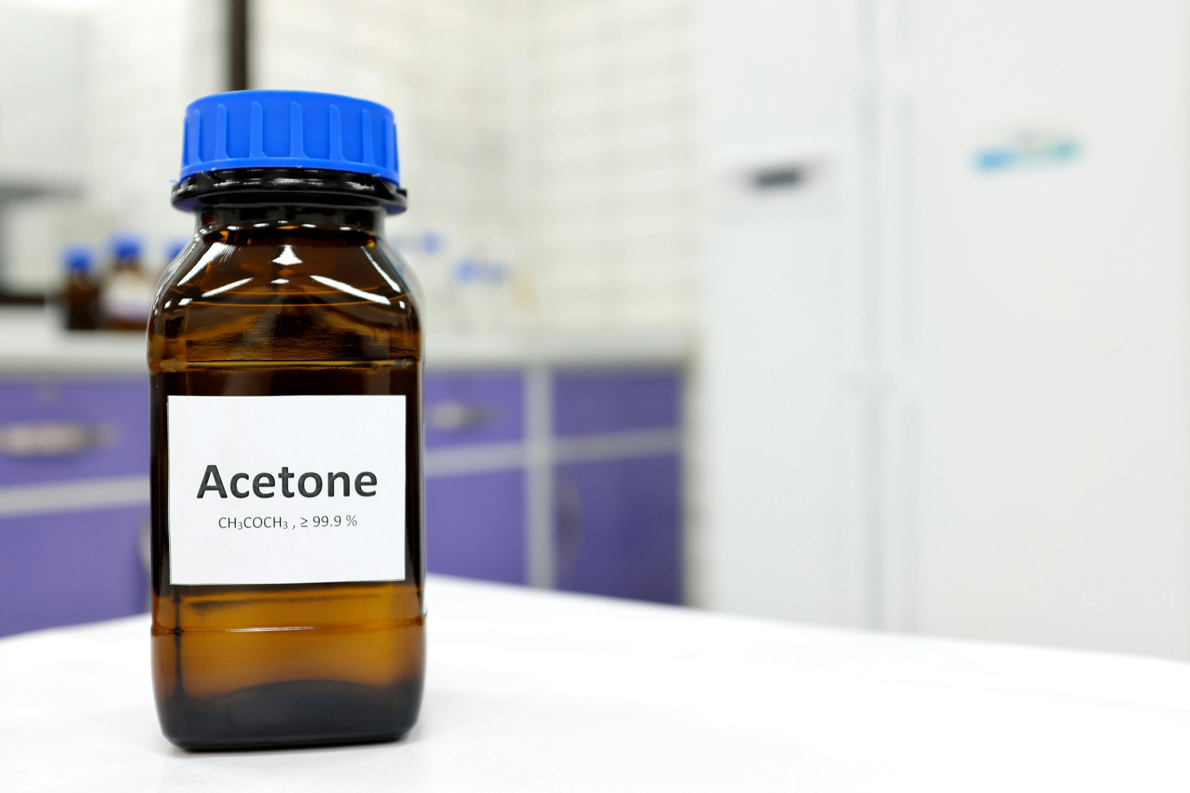 Selective focus of pure acetone solution in brown glass amber bottle inside a chemistry laboratory. White background with copy space. | Image Credit: © sulit.photos - stock.adobe.com