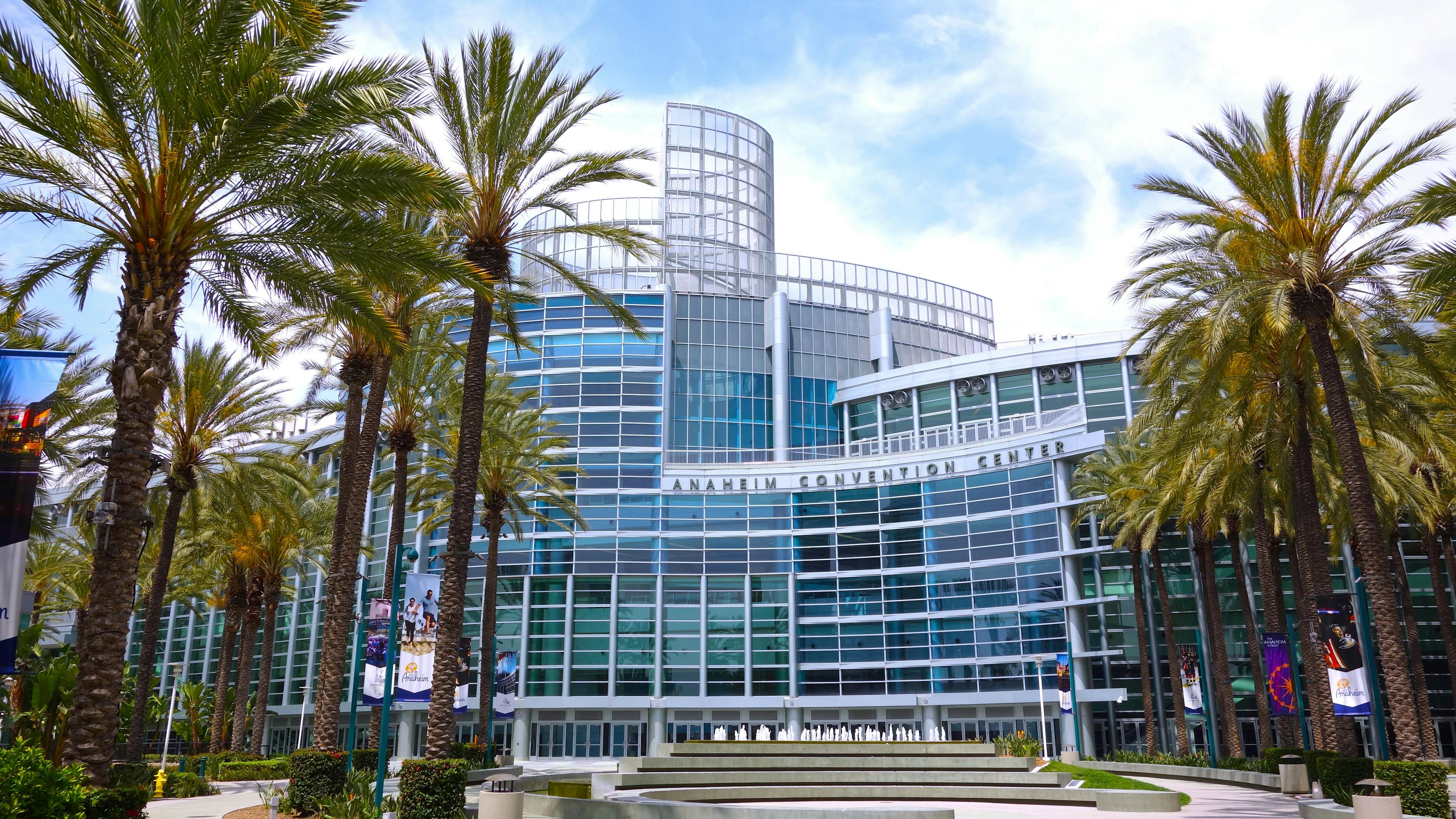 Wide shot of the Anaheim Convention Center with palm trees and fountain. Photo taken July 22, 2019 in Anaheim, CA / USA. | Image Credit: © Simone - stock.adobe.com