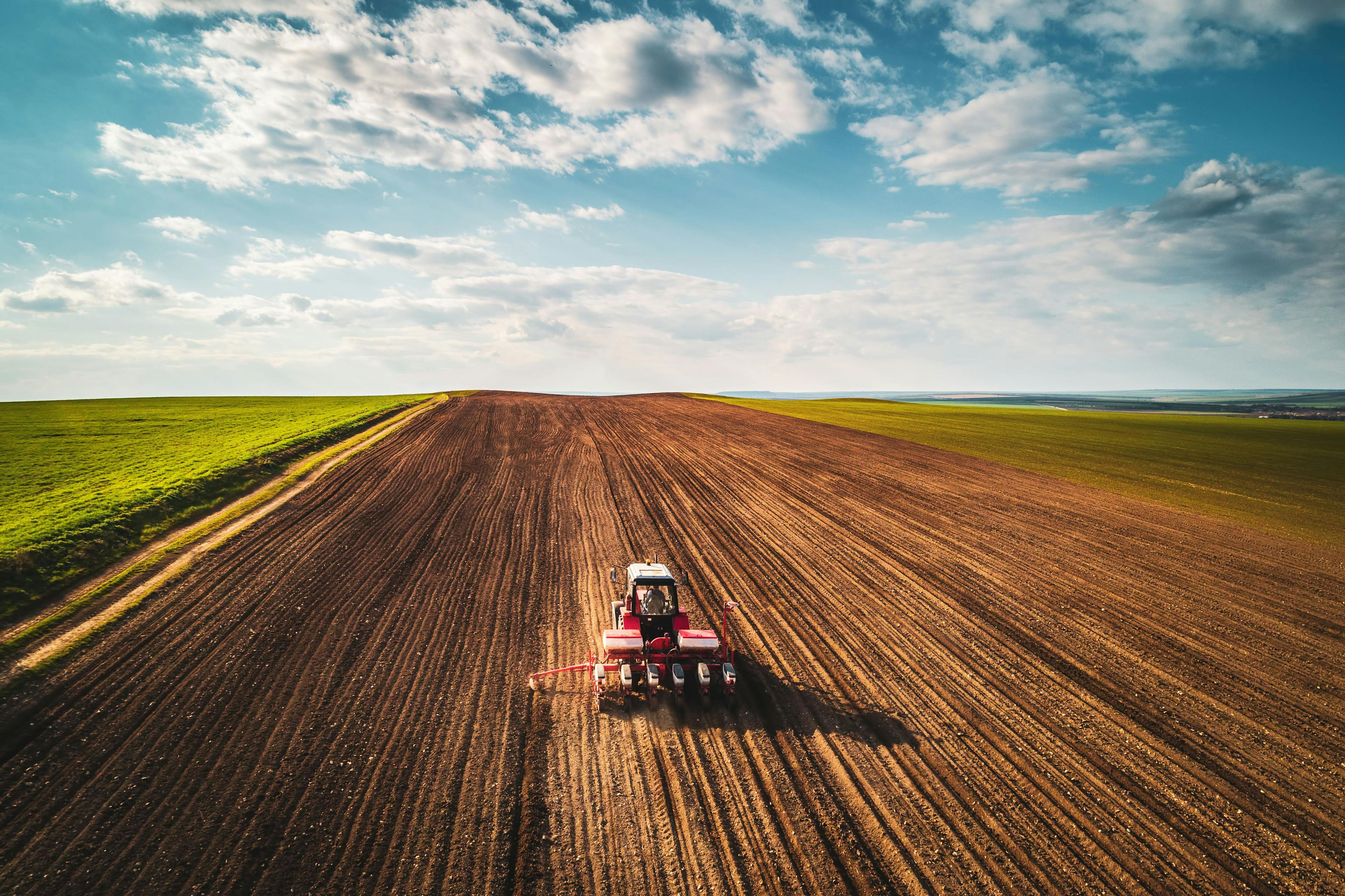 Farmer with tractor seeding crops at field, aerial view | Image Credit: © ValentinValkov - stock.adobe.com.