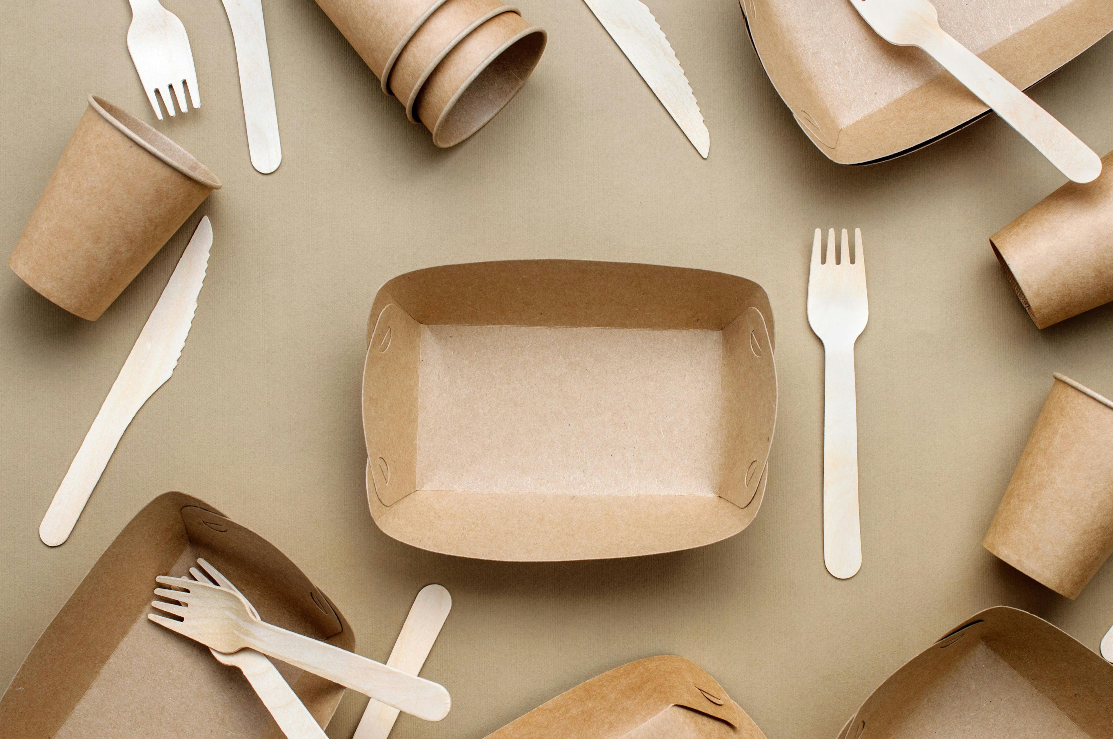 Brown kraft paper food containers, forks and knifes on beige background | Image Credit: © lithiumphoto - stock.adobe.com