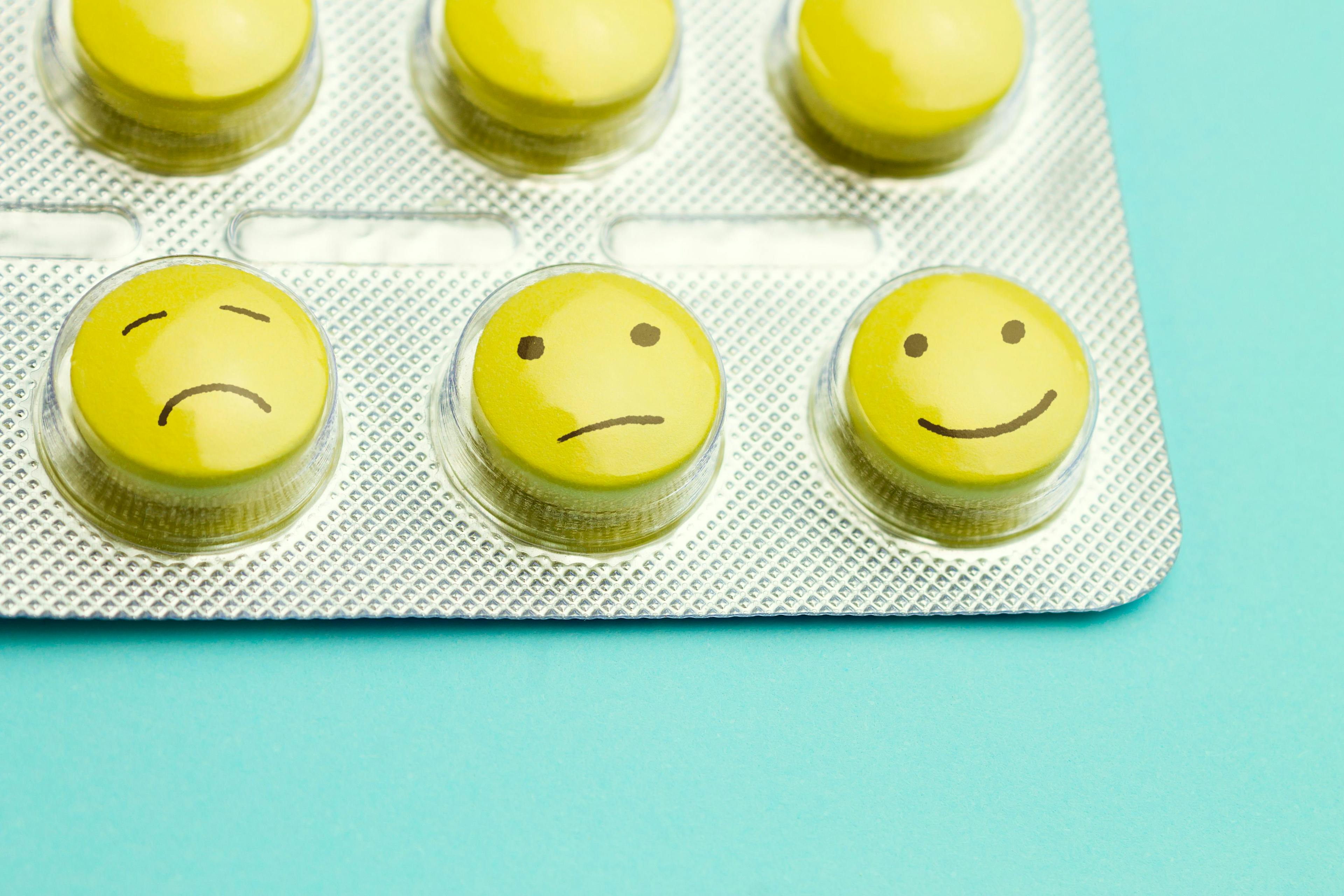 Yellow pills and funny faces in a blister on a blue background. The concept of antidepressants and healing | Image Credit: © TanyaJoy - stock.adobe.com