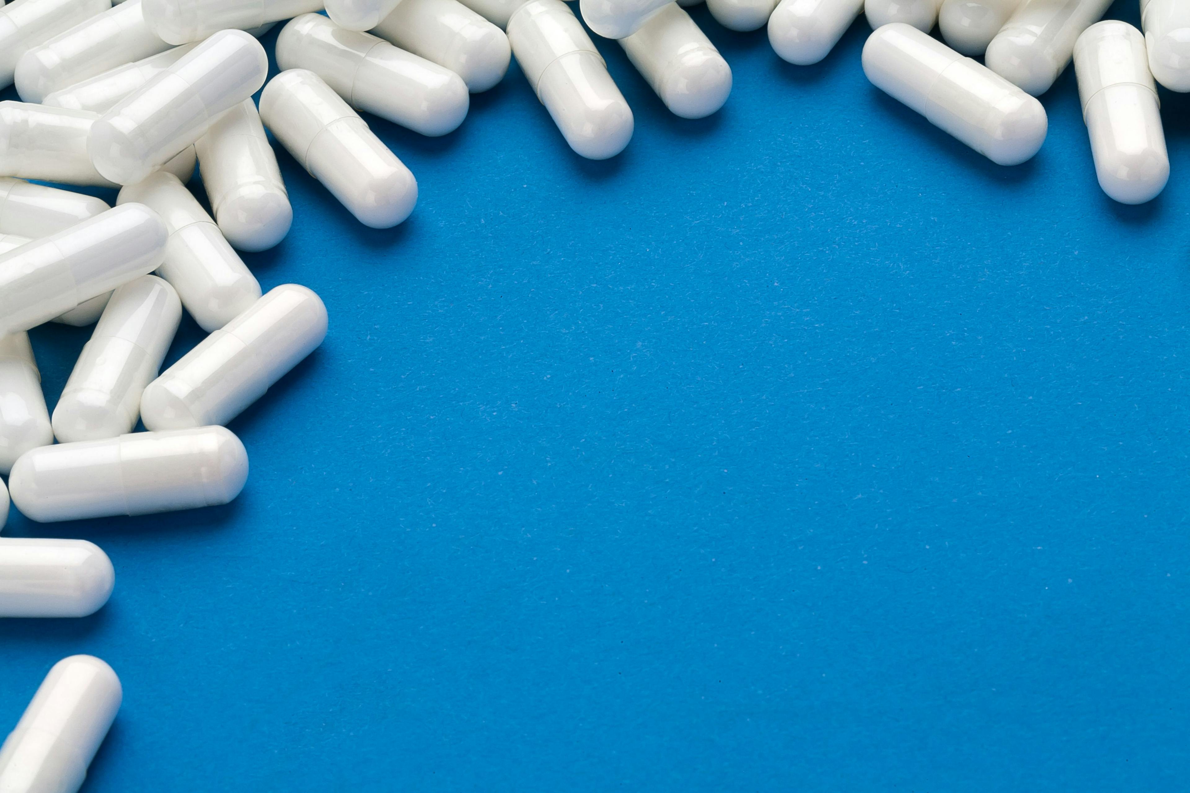 White capsules medications on blue background. | Image Credit: © Romario Ien - stock.adobe.com. 