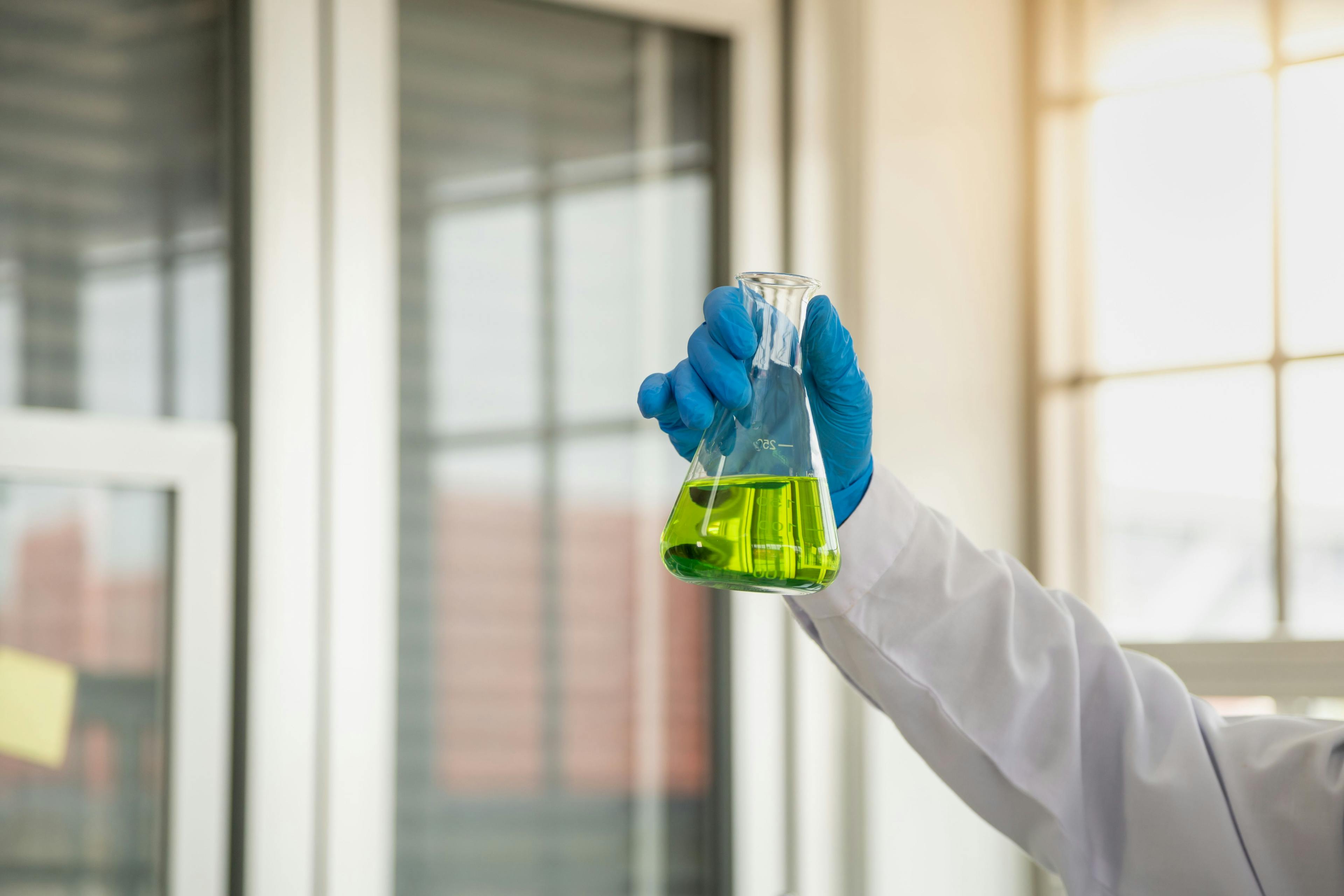 Science and Healthcare Concept. Closeup of doctor scientists hand holding green liquid chemicals flask in a laboratory. | Image Credit: © Montri Thipsorn - stock.adobe.com.