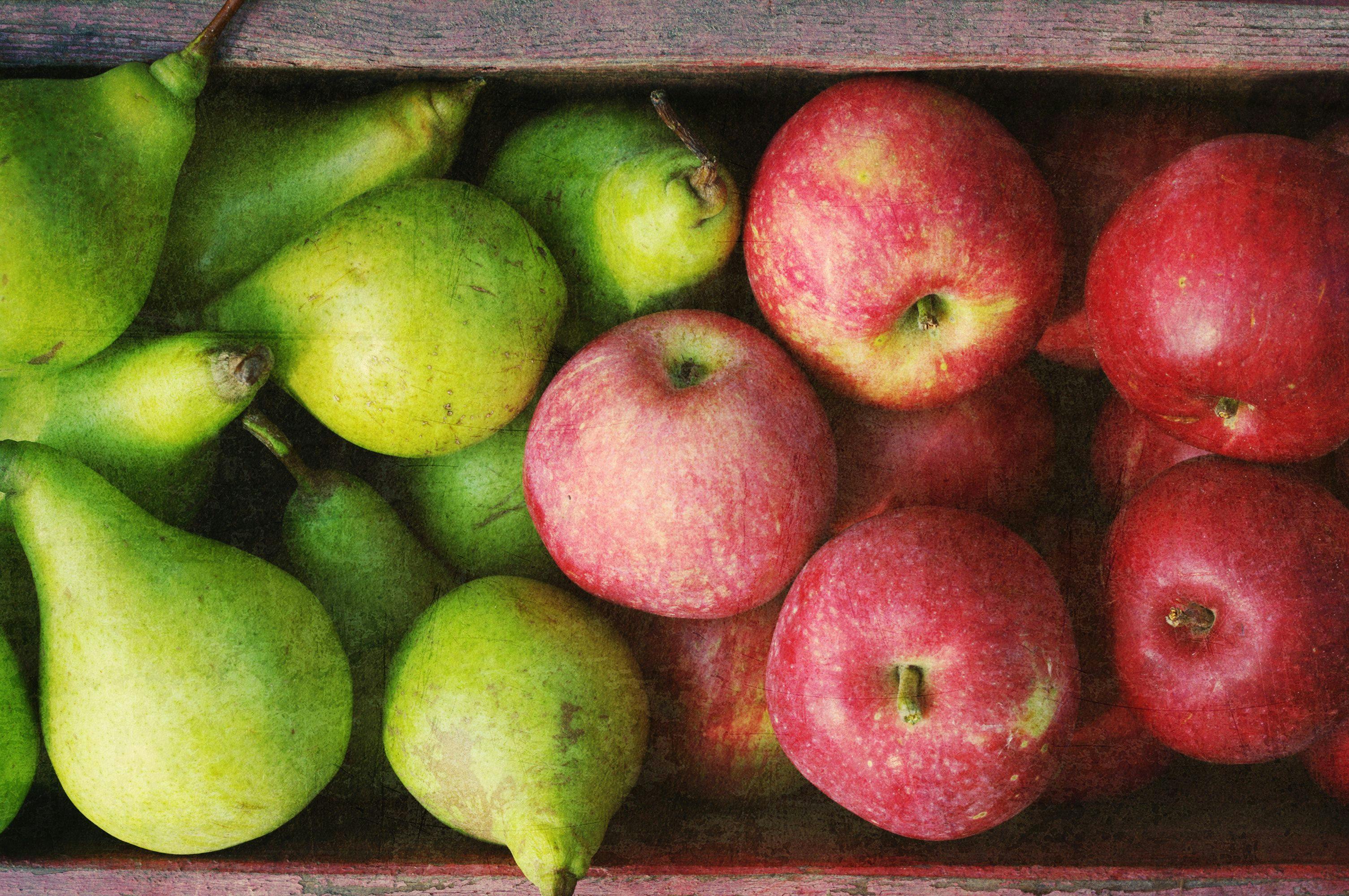 Ripe green pears and red apples in a wooden box with grunge texture, top view. Autumn harvest of pears | Image Credit: © isavira - stock.adobe.com