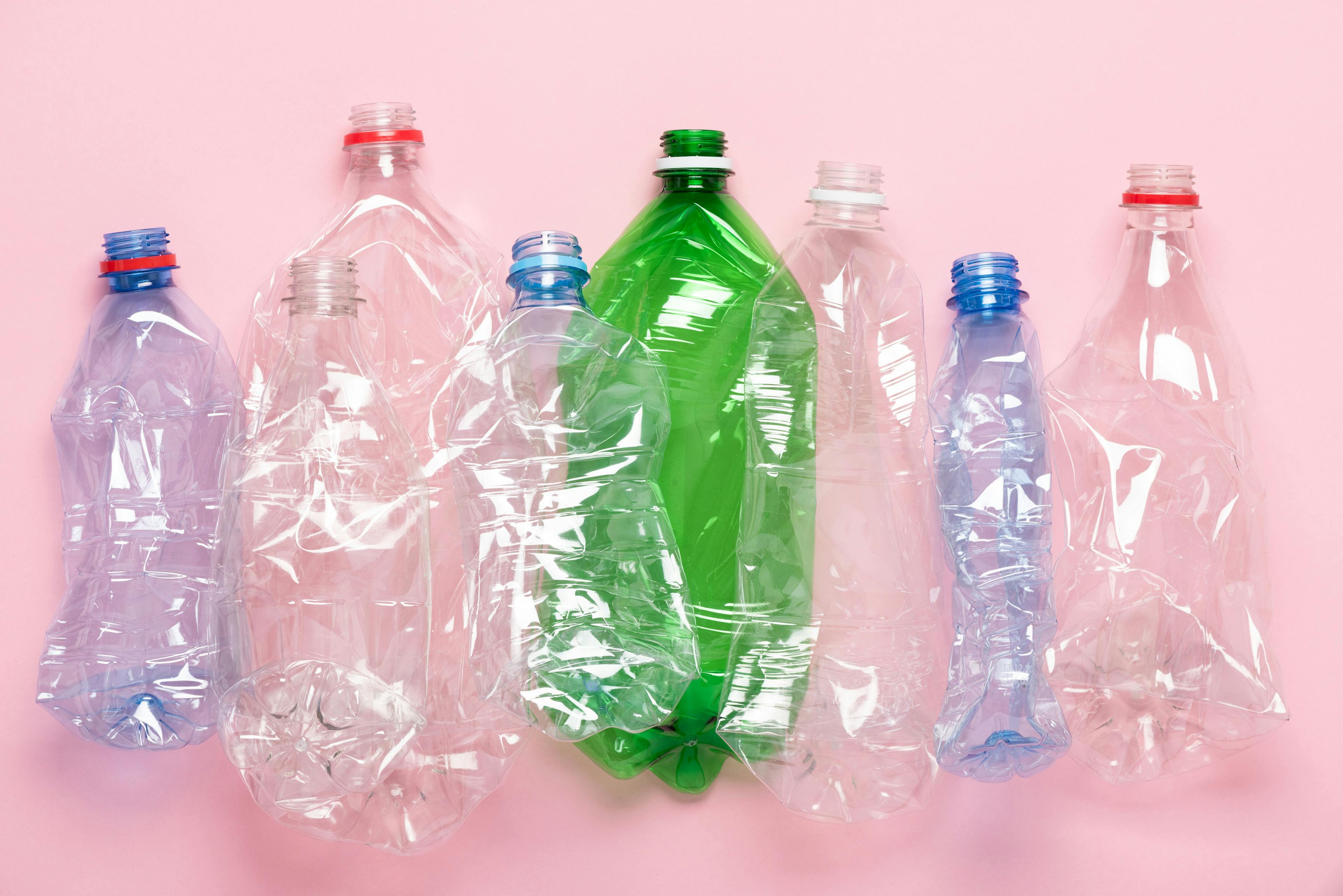 Plastic bottles on pink pastel background top view. Eco plastic recycling concept. | Image Credit: © nevodka.com - stock.adobe.com