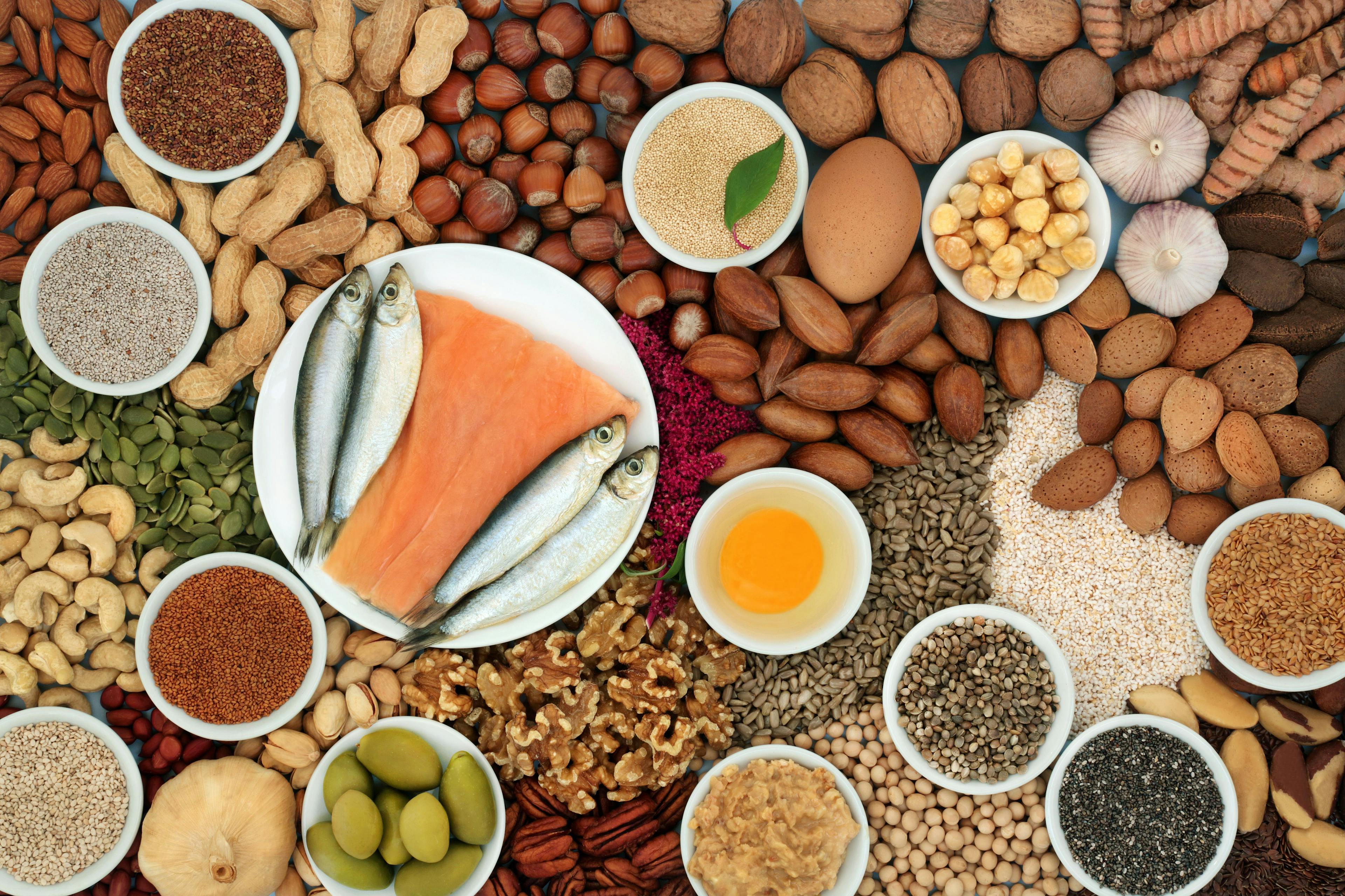 Healthy heart food ingredients high in lipids containing unsaturated good fats for low cholesterol levels with nuts, seeds, dairy, fish, vegetables, legumes and grain. Top view. | Image Credit: © marilyn barbone